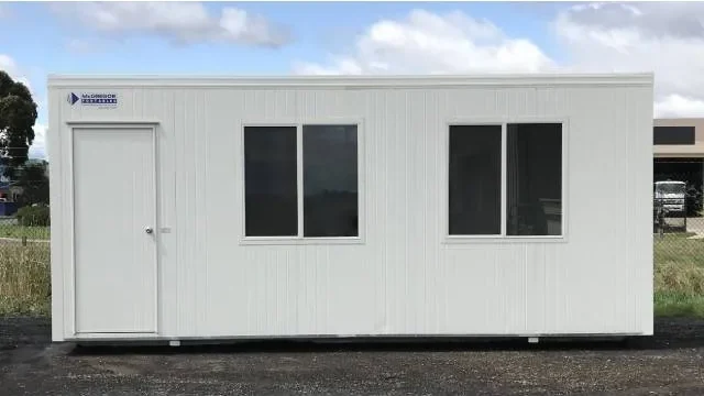White used McGregor portable building with an entry door and two windows, on a gravel yard