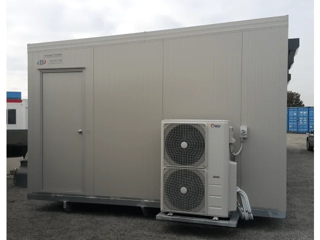 Grey building with a single entry door and two stacked outdoor condenser units mounted at the right-hand end.