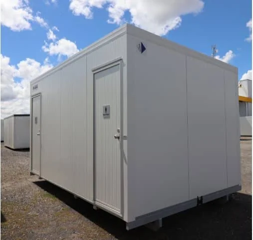 White toilet block seen from the corner, with one door on the near end and blank cladding along the side.