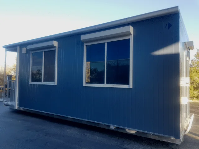 Blue eco lunchroom with two awning-shaded windows along the side, standing on grass.