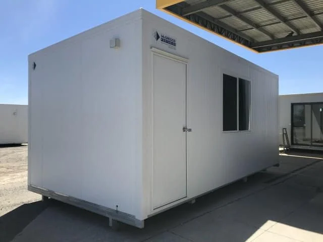 White repackaging room with a single door and a small window, standing under a shed roof.