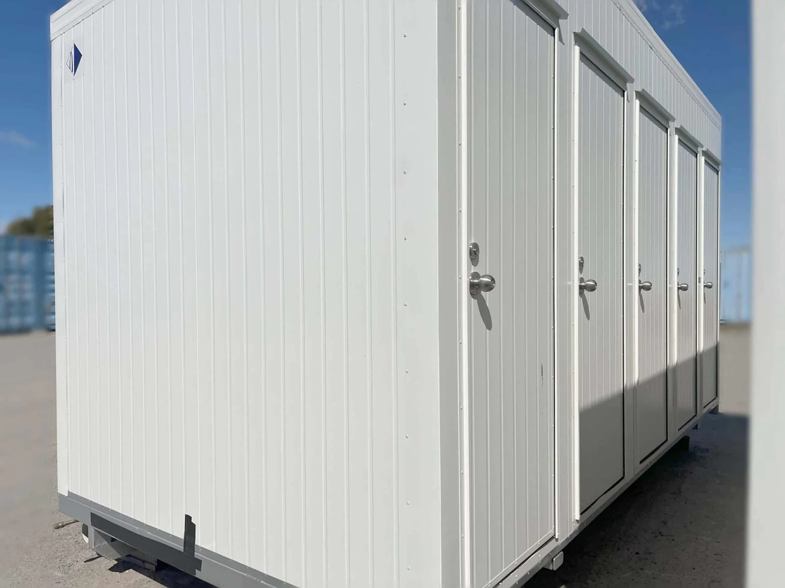 White unisex toilet block seen from the corner, with a run of doors along the side.