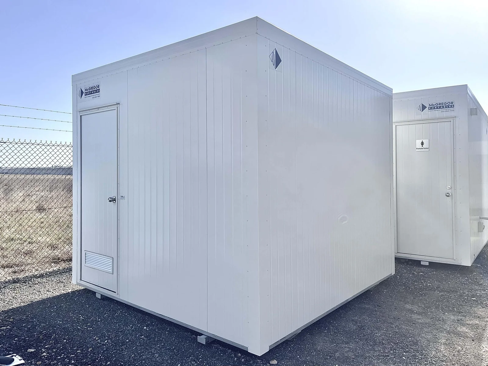 White storage room with a single door and blank cladding, with another unit standing behind it.