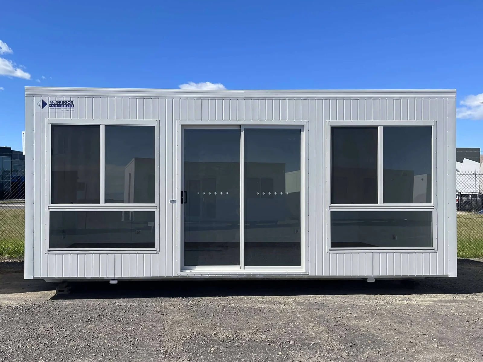 White sales office with a central sliding glass door set between two large windows.